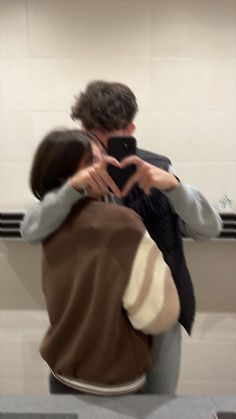 a man and woman taking a selfie in front of a mirror with their cell phone