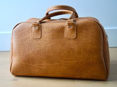 A seventies vintage travel bag brown coloured vinyl. The bag can be carried either with the briefcase style handle on top. In good condition with some mark. (look photo) Size 15x8 Brown Travel Bag With Top Carry Handle For Trips, Vintage Brown Travel Bag With Leather Handles, Vintage Brown Satchel For Trips, Retro Cognac Shoulder Bag For Travel, Vintage Satchel For Trip, Brown Briefcase With Luggage Sleeve For Trips, Vintage Rectangular Travel Bag With Top Carry Handle, Vintage Brown Travel Bag For Everyday, Vintage Brown Weekender Bag For Travel