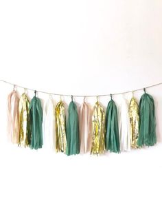 some tassels are hanging on a string with gold foil and green tissue pom - poms