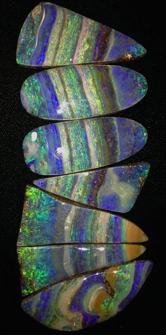 four pieces of opalite sitting on top of a black surface with green and blue stripes