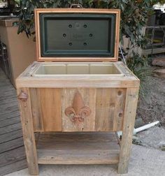 an old wooden cooler with a fleur de lis emblem on the front and side