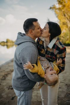 a man and woman kissing each other on the beach with trees in the back ground