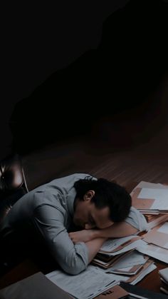 a man laying on the floor with his head in his hands and papers scattered around him