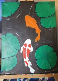 a painting of a koi fish and lily pads on a black background with green leaves