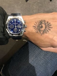 a man with a tattoo on his arm and wrist is holding onto a blue watch