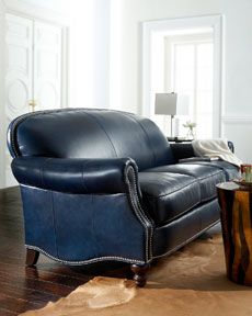 a blue leather couch sitting on top of a hard wood floor next to a table