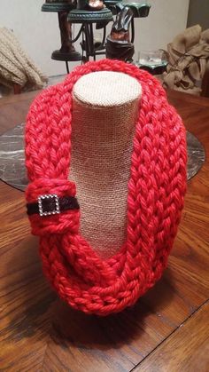 a mannequin wearing a red knitted scarf on top of a wooden table