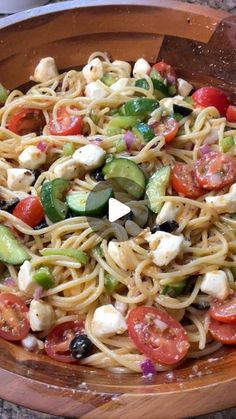 a wooden bowl filled with pasta and veggies