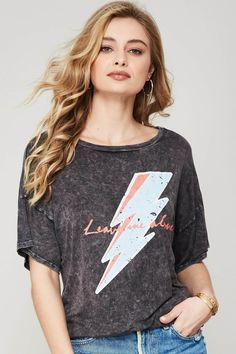 Stone-washed graphic t-shirt. Vintage-style lightning bolt graphic print with "Leave Me Alone" text. Longline silhouette. Curved dolphin hem. Round neckline. Short drop-shoulder sleeves. Loose fit. Designed and manufactured in Los Angeles, CA. Shown with Twill Out Pocket Mini Skirt. Acid Wash Relaxed Fit Slogan Top, Acid Wash Slogan Top With Relaxed Fit, Trendy Acid Wash Tops With Screen Print, Relaxed Fit Acid Wash Slogan Top, Relaxed Fit Acid Wash Top With Slogan, Edgy Washed Tops For Spring, Rebellious Crew Neck T-shirt For Summer, Rebellious Summer Crew Neck T-shirt, Edgy Soft-washed T-shirt For Spring