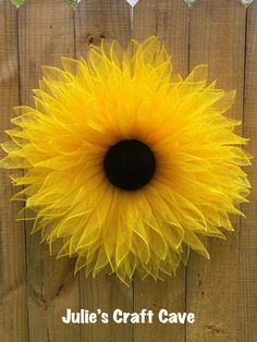 a yellow sunflower is hanging on a fence with the words julia's craft cave above it