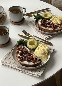 two plates with food on them sitting on a table next to cups and utensils