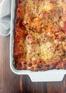 a casserole dish with meat and cheese in it sitting on a wooden table