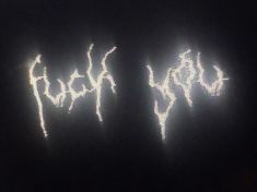 some type of graffiti written on the side of a building at night with bright lights