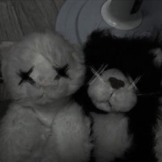 two black and white teddy bears with crosses on their eyes sitting next to each other