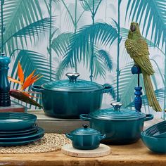 a table topped with blue pots and pans covered in green bird figurines