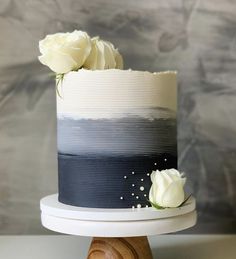 a white rose on top of a black and white striped cake with two roses in the middle