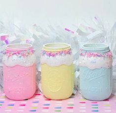 three jars filled with different colored confetti and sprinkles on top of a table