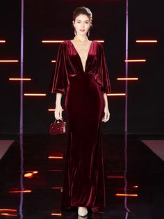 a woman in a red velvet dress on the runway