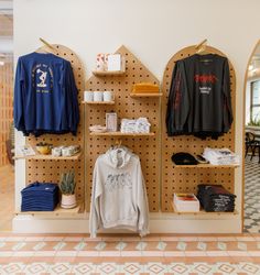 a clothing store display with shirts and sweaters hanging on pegboards in front of them