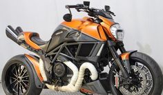 an orange and black motorcycle is parked in a room with a white wall behind it