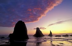 the sun is setting over some rocks in the water