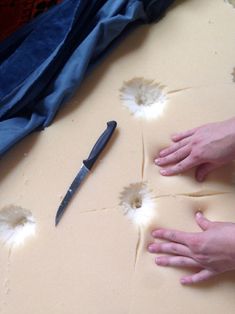 someone is peeling off the edge of a mattress with their hands and knife on it