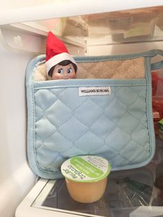 the elf is hiding in the fridge with his food and icecream container on the shelf