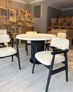 several chairs and tables in a room full of wooden chairs, one with a round table