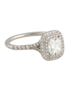 a white gold ring with an oval cut diamond surrounded by small round brilliant pave diamonds