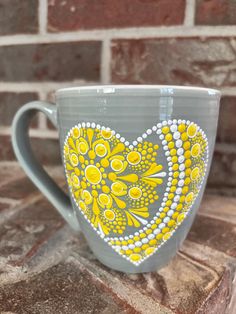 a yellow and gray heart shaped coffee cup sitting on top of a brick countertop