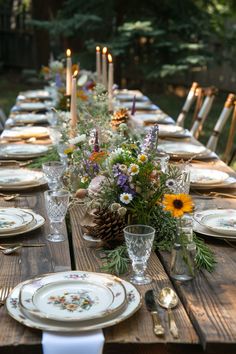 a long table set with plates and place settings for an outdoor dinner party in the woods