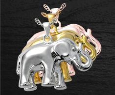 two silver and gold elephant pendants on a black background with the words love is in the air