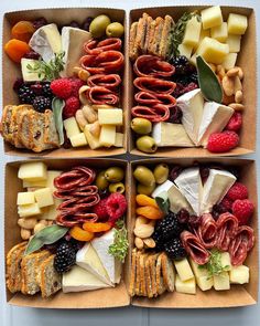 four boxes filled with different types of cheeses and meats on top of each other