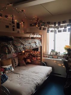 a bunk bed in a dorm room with lights strung from the ceiling and curtains on the windowsill