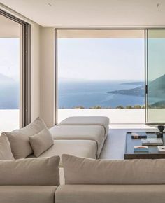 a living room filled with furniture and a large window overlooking the ocean in front of it