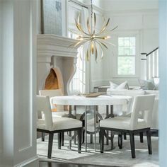 a dining room table with white chairs and a chandelier hanging from the ceiling