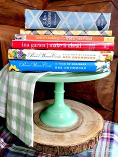 a stack of books sitting on top of a green cake plate next to a pile of books