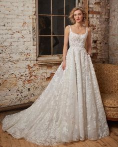 a woman standing in front of a window wearing a wedding dress