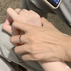 two hands holding each other with a cell phone in the background