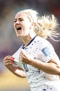 a female soccer player with her hair in the air and mouth wide open, screaming