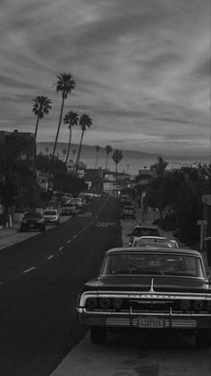 an old car is parked on the side of the road with palm trees in the background