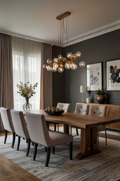 a dining room table with chairs and lights hanging from it's ceiling, in front of a large window