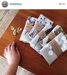 a person is holding a small plant in front of napkins on a wooden table