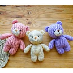 three crocheted teddy bears sitting next to each other on a wooden table top