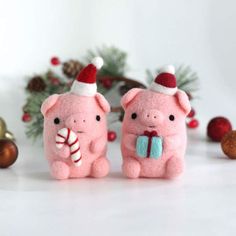 two pink pigs with hats and candy canes on white surface next to christmas decorations