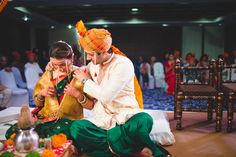 a bride and groom sitting on the floor in front of an audience at a wedding