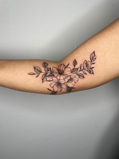 a woman's arm with flowers and leaves on it