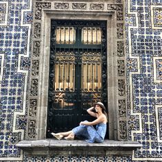 a woman sitting on a ledge in front of a door