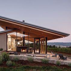 a modern house with an outdoor fireplace in the middle of it's patio area