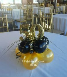 the table is set with balloons and decorations for an anniversary celebration in gold and black